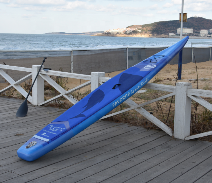 Blue half V-hull full-print race inflatable SUP paddleboard side view on a seaside boardwalk