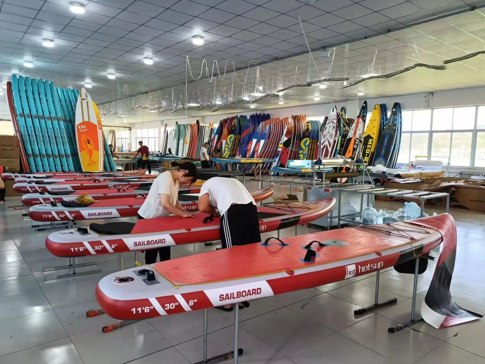 Factory workers assembling red paddleboards on production line