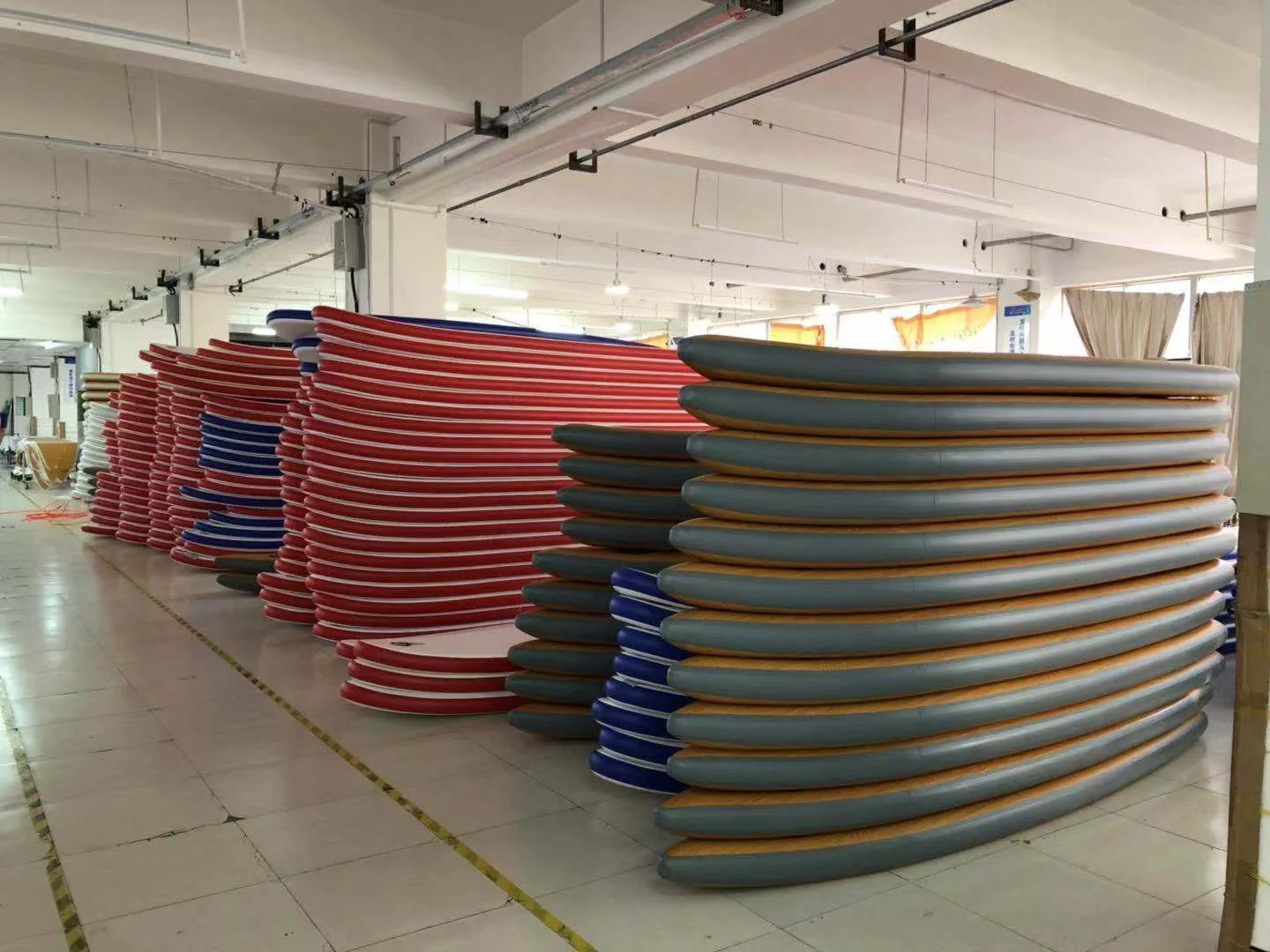 Colorful inflatable stand up paddle boards stacked in a manufacturer warehouse