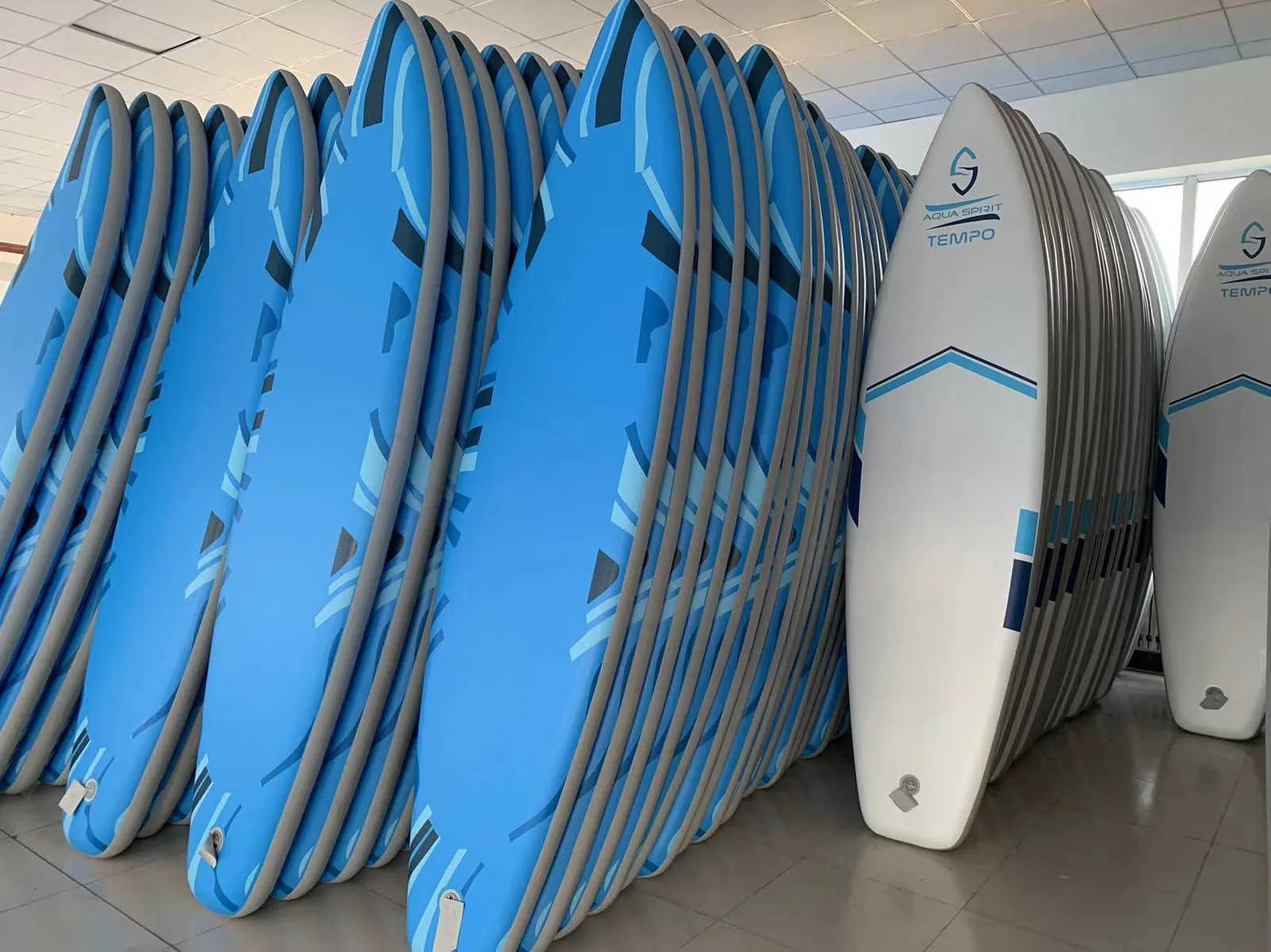 Stacked blue inflatable SUP boards shown in side view in a factory